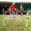 bambino con maglietta arancione che gioca al salto agli ostacoli